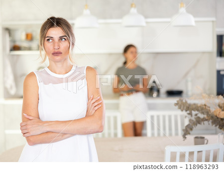 Serious woman is standing in kitchen and thinking about something Serious woman is standing in kitchen and thinking about something 118963293