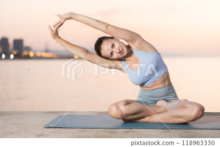 Near sea during sunset, girl performs variations of padmasana with body tilt Near sea during sunset, girl performs variations of padmasana with body tilt 118963330
