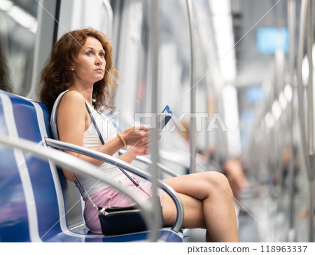 Portrait of a woman holding a smartphone in subway car 118963337