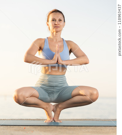 Near sea during sunset, girl performs prapadasana 118963437