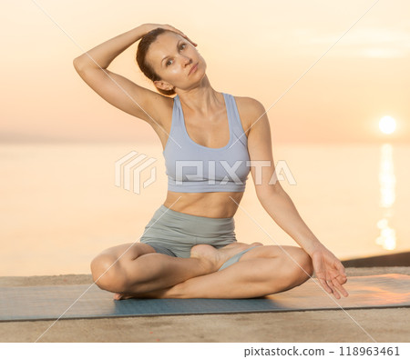 Near sea during sunset, girl performs variations of padmasana with body tilt Near sea during sunset, girl performs variations of padmasana with body tilt 118963461