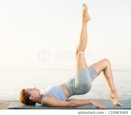 Near sea during sunset, girl performs Setu Badha Sarvangasana Near sea during sunset, girl performs Setu Badha Sarvangasana 118963469