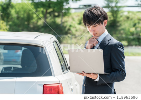 一名年輕的亞洲男子，在汽車經銷店擔任評估師/推銷員，正在評估汽車 118963696