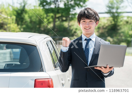 一名年輕的亞洲男子,在汽車經銷店擔任評估師/推銷員,正在評估汽車 一名年輕的亞洲男子,在汽車經銷店擔任評估師/推銷員,正在評估汽車 118963701