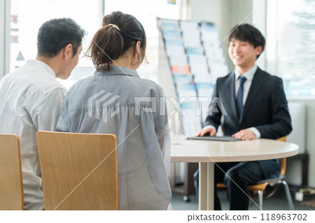 一位年輕的亞洲商人和一對客戶夫婦在陳列室/商務談判空間為客戶提供服務 118963702