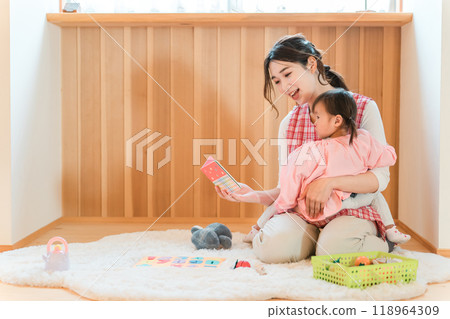 A female nursery teacher, nursery teacher, or sitter reading a picture book to a girl at a nursery school, kindergarten, daycare center, or daycare center A female nursery teacher, nursery teacher, or sitter reading a picture book to a girl at a nursery school, kindergarten, daycare center, or daycare center 118964309