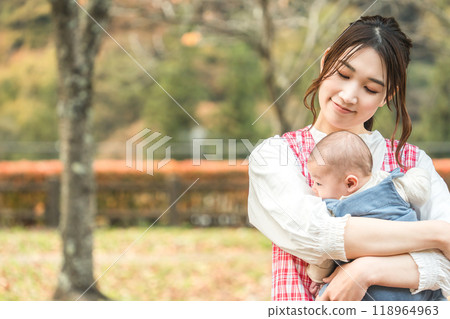 A babysitter woman and a kindergarten child (nursery school, kindergarten, nursery teacher, nursery school teacher) walking in the autumn park 118964963
