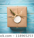 Gift tag mockup. Top view round blank white circle sticker for brand logo label design with brown kraft paper box on blue wooden table background. AI generated 118965253