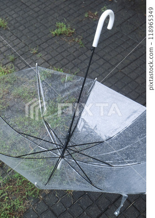 A plastic umbrella with raindrops on it, lying on the ground 118965349