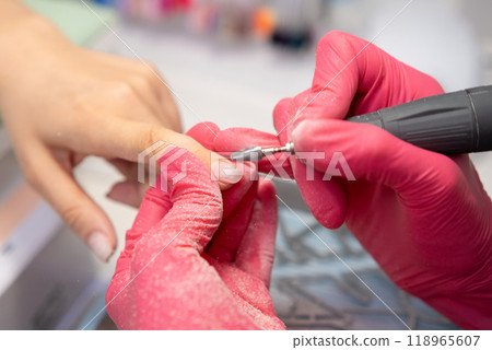 Manicure master using a nail drill machine for manicure service in a modern salon.  118965607