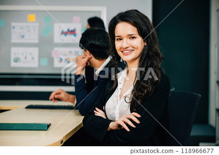 Within the meeting room, a businesswoman's portrait mirrors her expertise and leadership. The proud CEO, diverse colleague, and manager epitomize success through strategic teamwork and planning. 118966677