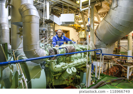 Marine Engineer in blue overall working in Engine room of ship. Work at sea. Motorman. Marine Engineer in blue overall working in Engine room of ship. Work at sea. Motorman. 118966749
