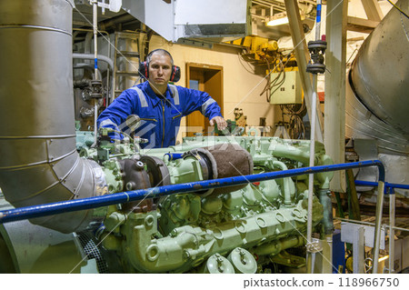 Marine Engineer in blue overall working in Engine room of ship. Work at sea. Motorman. Marine Engineer in blue overall working in Engine room of ship. Work at sea. Motorman. 118966750