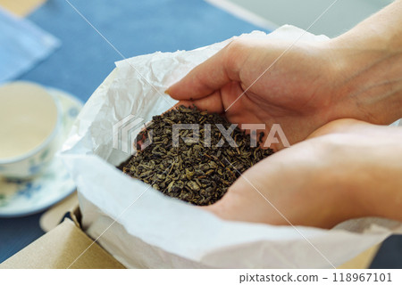 Woman holding paper bag with dry green tea leaves, close up Woman holding paper bag with dry green tea leaves, close up 118967101