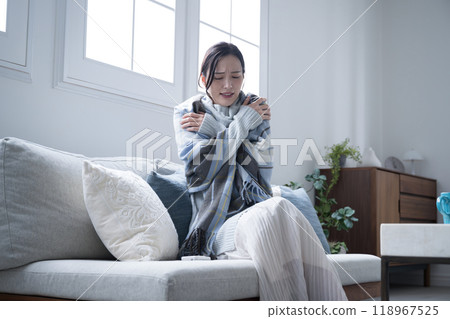 A woman struggling with the coldness of her room in winter at home - Measures to prevent colds and poor circulation - Wide-angle full-body shot 118967525