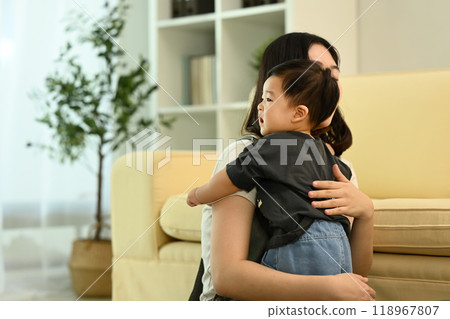 Loving mother playing with her baby on a comfortable sofa in cozy living room 118967807