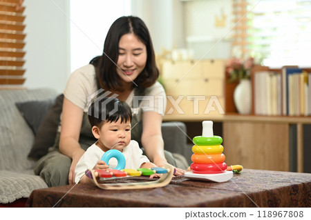 An adorable little boy and mother playing with colorful toys in a cozy living room 118967808