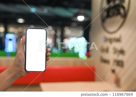 Hand holding a smartphone with a blank screen on blurred coffee shop background Hand holding a smartphone with a blank screen on blurred coffee shop background 118967869