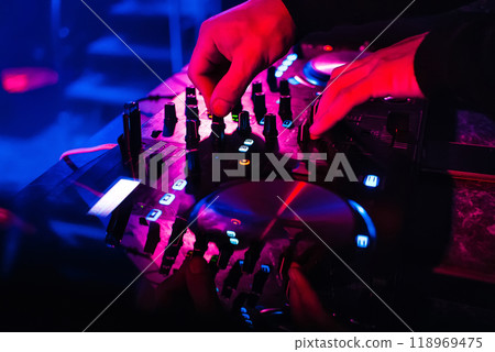 DJ mixes and controls controls music on professional equipment DJ mixes and controls controls music on professional equipment 118969475