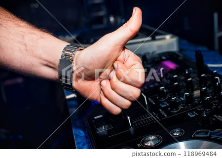 hand of DJ shows the class background of switchers and remote control in nightclub hand of DJ shows the class background of switchers and remote control in nightclub 118969484