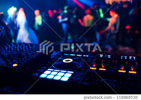 control DJ for mixing music with blurred people dancing at party in nightclub 118969530