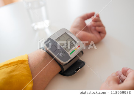 Close up of woman checks her blood pressure, a tonometer is worn on her wrist. Medical device for measuring blood pressure and heart rate used at hand wrist Close up of woman checks her blood pressure, a tonometer is worn on her wrist. Medical device for measuring blood pressure and heart rate used at hand wrist 118969988