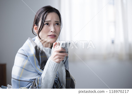 Woman having difficulty adjusting air conditioner in winter - Close-up 118970217