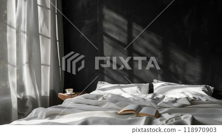 The minimalist bedroom features a large bed adorned with crisp white linens, a book laid open on the covers, and sunlight filtering through sheer curtains 118970903