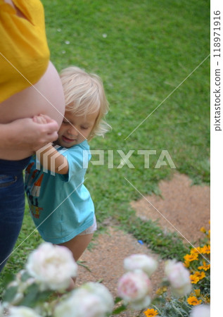 Moments of pregnancy. Little daughter listening to her brother in the belly of her pregnant mother. Moments of pregnancy. Little daughter listening to her brother in the belly of her pregnant mother. 118971916