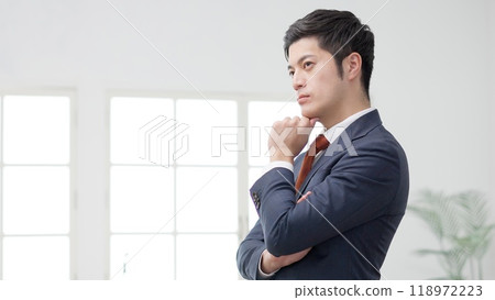 A worried businessman with his hand on his chin 118972223