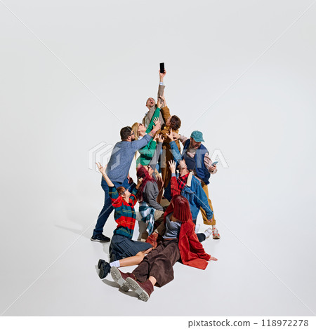 Crowd of people forming a human tower, showing their excitement to get the best shopping deals. Trying to grab mobile phone in male hand. 118972278