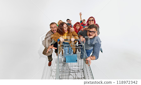 Group of emotional people dressed in stylish autumn outfits, fighting for the best shopping deals, pushing shopping cart forward 118972342
