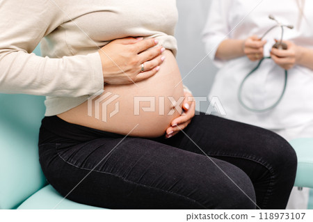 Female doctor using stethoscope examining pregnant woman in clinic. Medical exam pregnant woman 118973107