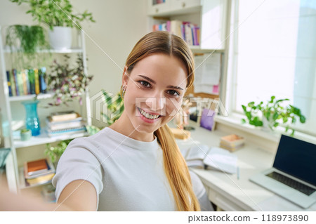 Close-up selfie portrait of teenage cheerful female looking at web camera 118973890