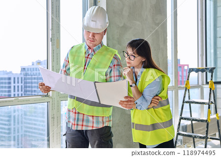 Colleagues in protective vest helmet working together on new construction site 118974495