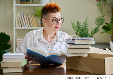Woman with new books unpacked from cardboard box 118974508