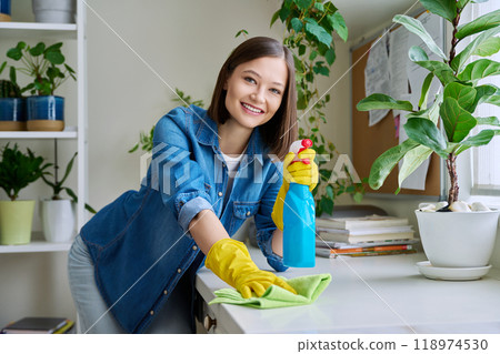 Portrait of young woman cleaning house, wearing gloves with cleaning spray looking at camera 118974530