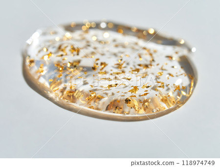 Transparent gel texture with gold flakes on white background reflecting modern 118974749