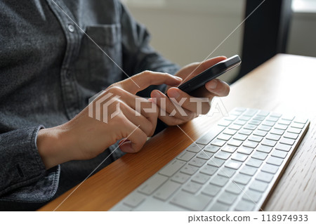 The user is using the index finger of his right hand to tap and flick the screen of a smartphone held in his left hand. The user is using the index finger of his right hand to tap and flick the screen of a smartphone held in his left hand. 118974933