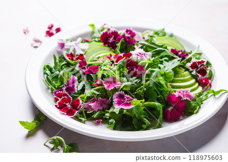 Green salad with apple and pink culinary flowers on white plate, on pink marble background. 118975603