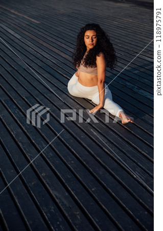 Athletic woman doing gymnastics yoga asana on wooden floor 118975791