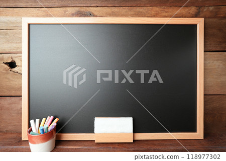 Black chalkboard with  colorful chalks and eraser on wooden wall 118977302