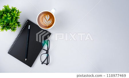 Top view white workspace office desk with office supplies. Flat lay work table with black notebook, Green leaf and coffee cup, Copy space for your advertising content. Top view white workspace office desk with office supplies. Flat lay work table with black notebook, Green leaf and coffee cup, Copy space for your advertising content. 118977469