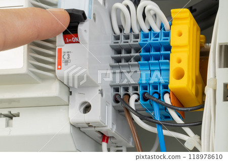 Hand turning on electrical circuit breaker in panel 118978610