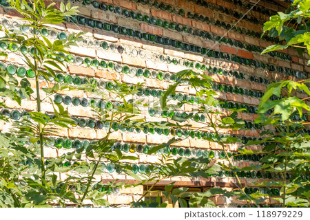 The wall of the house is made of bricks and glass green bottles. The wall of the house is made of bricks and glass green bottles. 118979229