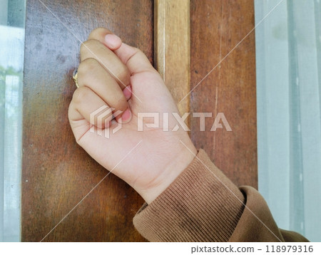 Hand knocking on a wooden door, Close up Knocking on the door, a woman's hand knocks on a wooden door, a visit to visit. 118979316