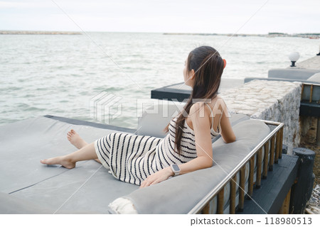 Beautiful asian woman resting on seat of balcony over tropical sea on vacation 118980513