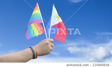 Cut out of hand holding both the LGBT flag and the Philippines flag, set against blue sky background with clipping paths. The symbolizing unity, diversity, and inclusion. 118980636