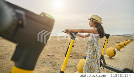 A girl is standing next to a yellow scooter. Summer time. Selective focus. 118981134