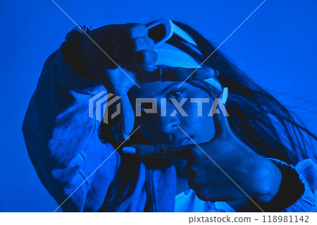 A woman is posing for a picture with her hands together in a frame. Urban dancer concept A woman is posing for a picture with her hands together in a frame. Urban dancer concept 118981142